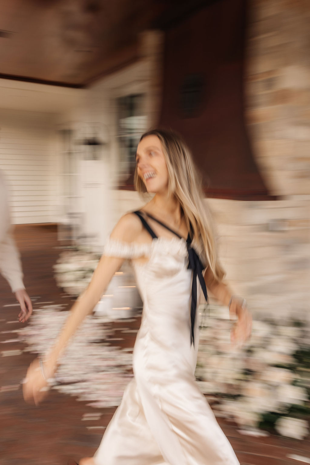 Blurry couple chasing each other around their flower arrangement after a proposal outside of The Study