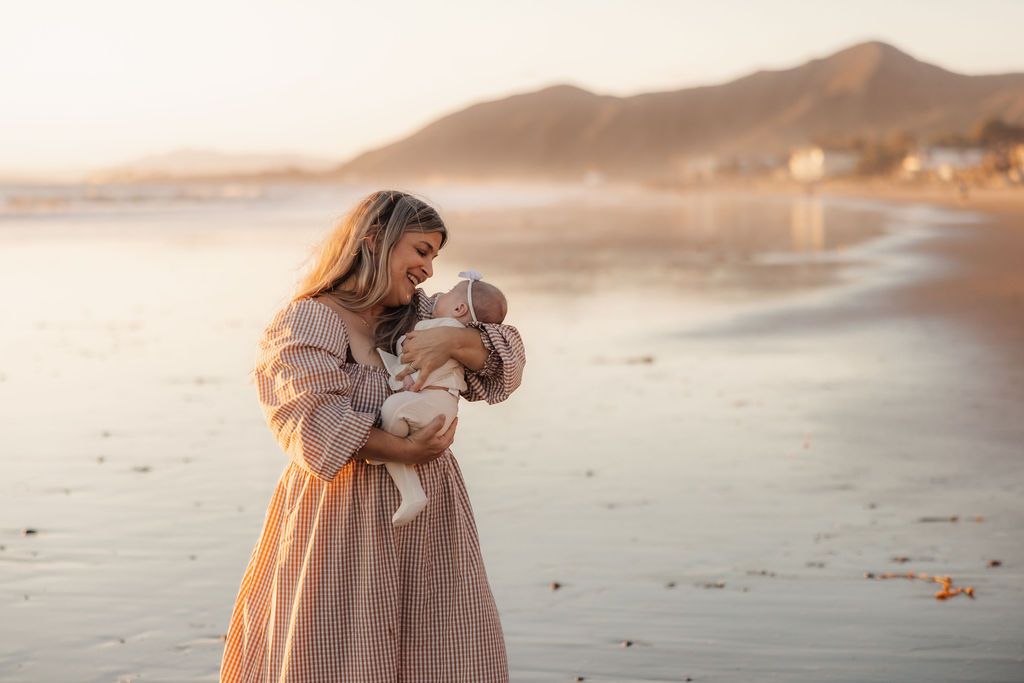 Loving moments between a mother and her newborn daughter by the ocean