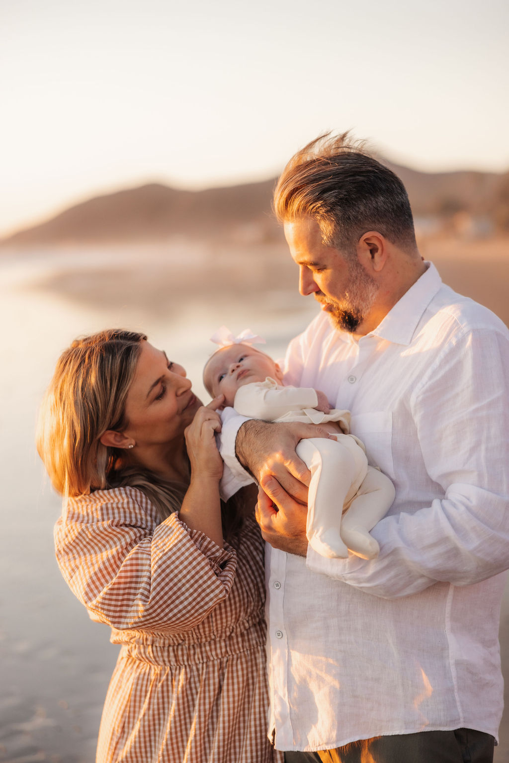 Parents and their new baby girl enjoying a peaceful sunset on a Ventura beach